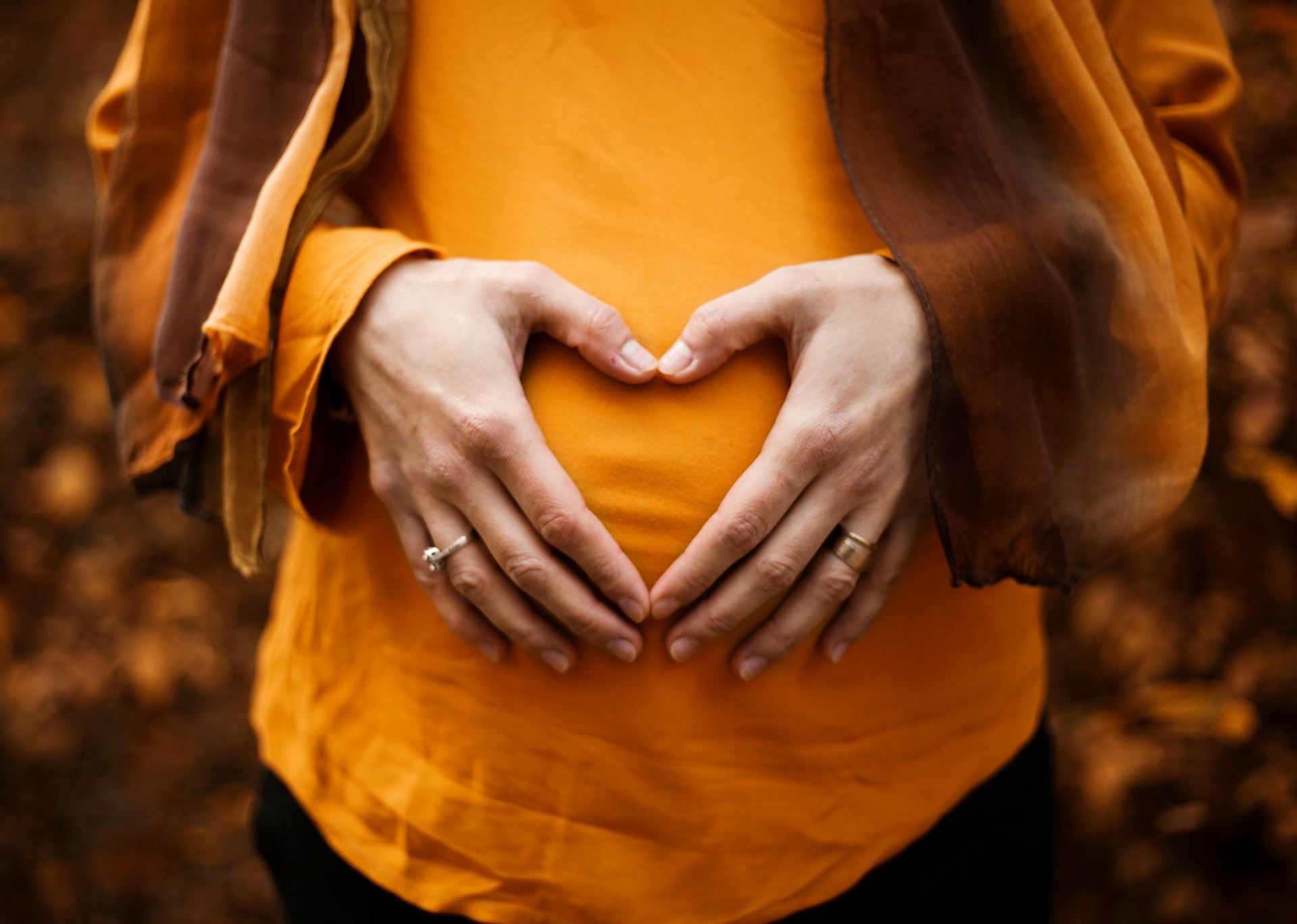 Hands making a heart over pregnancy bump
